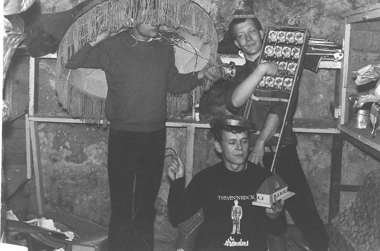 Photographie noir blanc ed trois jeunes, avec un abat-jour sur la tête